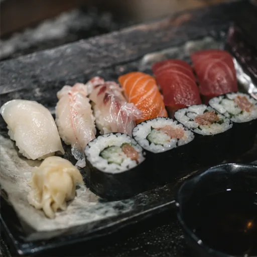 Piatto di sushi e sashimi appena preparato, banco in legno